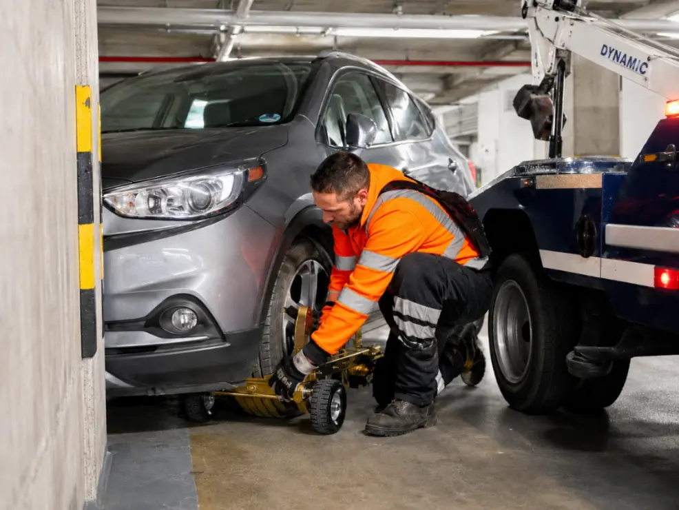 Tow truck operator using wheel dollies for low clearance towing Sydney in an underground car park