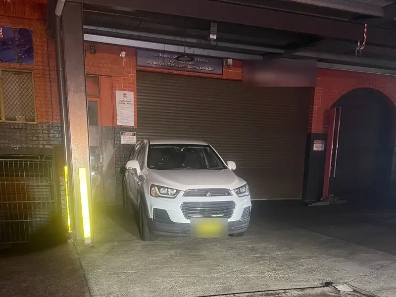 Jump start service Sydney: tilt tray tow truck reversing to collect an SUV from a workshop